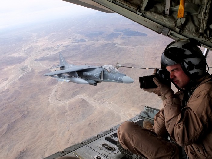 Gregory Moore đang "vê" nét từ đuôi chiếc vận tải cơ KC-130J Hercules, bên cạnh là một chiếc tiêm kích Harrier đang nhận dầu trên không